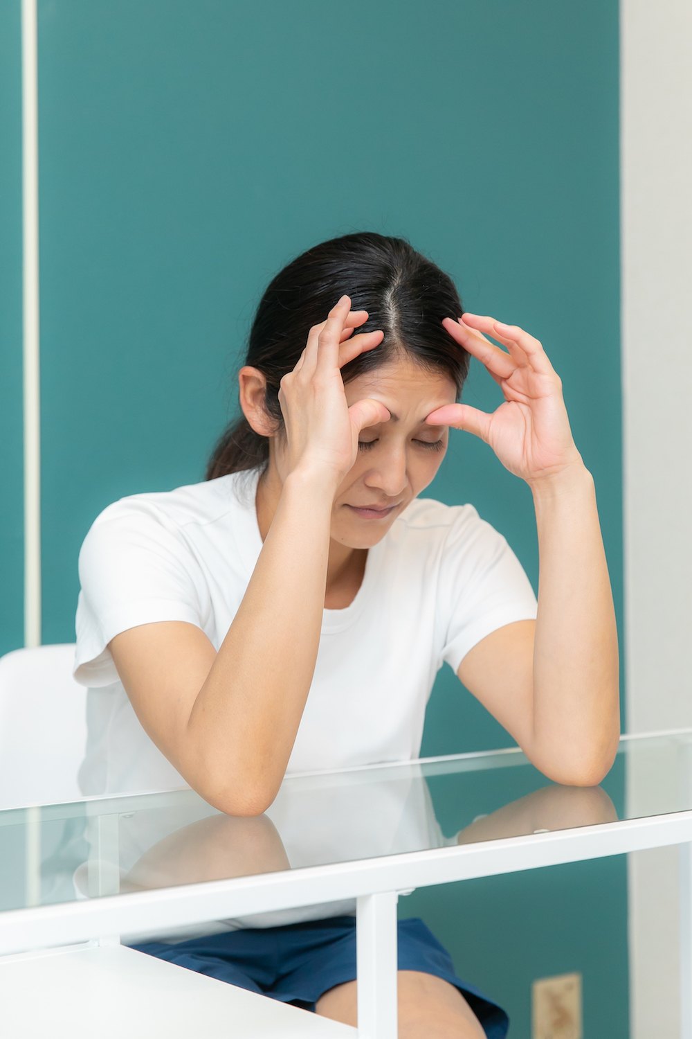 こめかみを両手で押さえている指圧の施術